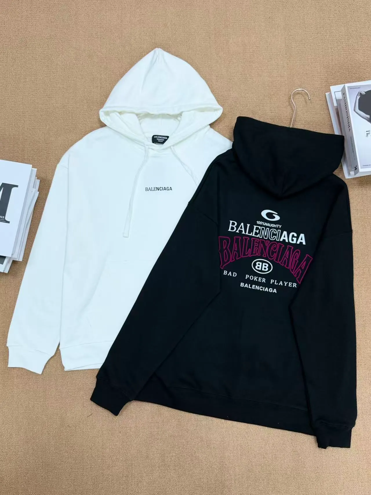 No. 2208 Style: Balenciaga Retro lettered hooded sweatshirt Color: Black, Cream White Version: Oversize loose shoulder, Same style for men and women, lazy and relaxed, covering the flesh and making you look slim Fabric: 430g high gram weight pure cotton terry fabric, soft and thick, with good drape, the upper body is not easy to wrinkle. Design highlights 1. White model: The small logo on the chest is simple and clean, minimalist and low-key style, and the daily Versatile is not picky. 2. Black model: Multi-layered Retro letter printing on the back, white rose red contrasting colors, strong layering, full of trendy atmosphere, the back printing is the visual focus of the entire dress. 3. Classic kangaroo pocket + adjustable drawstring brim, threaded cuffs and hem, Wear-Resistant is not easy to deform, and the workmanship is neatly routed. Wearing scenarios: Suitable for daily outings, commuting, and casual outings. Black is cool and stylish, and looks trendy when paired with jeans, wide-leg pants, and overalls; White is refreshing and simple, suitable for gentle casual style, and can also be worn as a couple's style. Washing and care tips: Machine wash/hand wash with cold water on the reverse side, do not rub the printed area vigorously, and dry in a cool place to avoid exposure to the sun, which may cause the print to crack and fade.